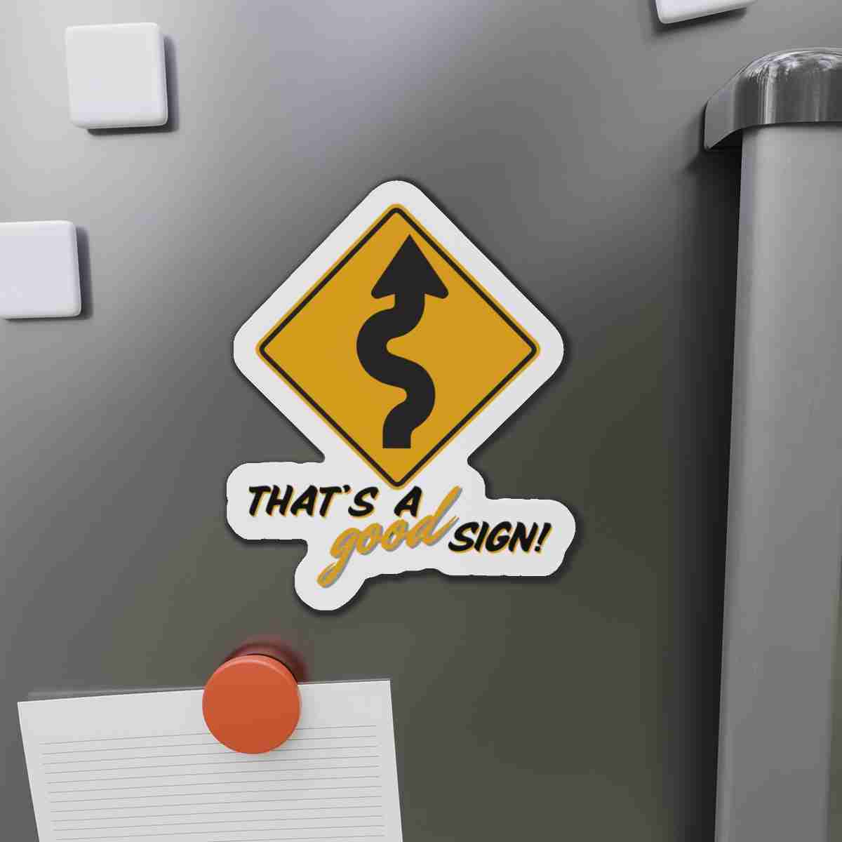 Decorative sticker of a winding road warning sign on a fridge, with text 'That's a good sign!'