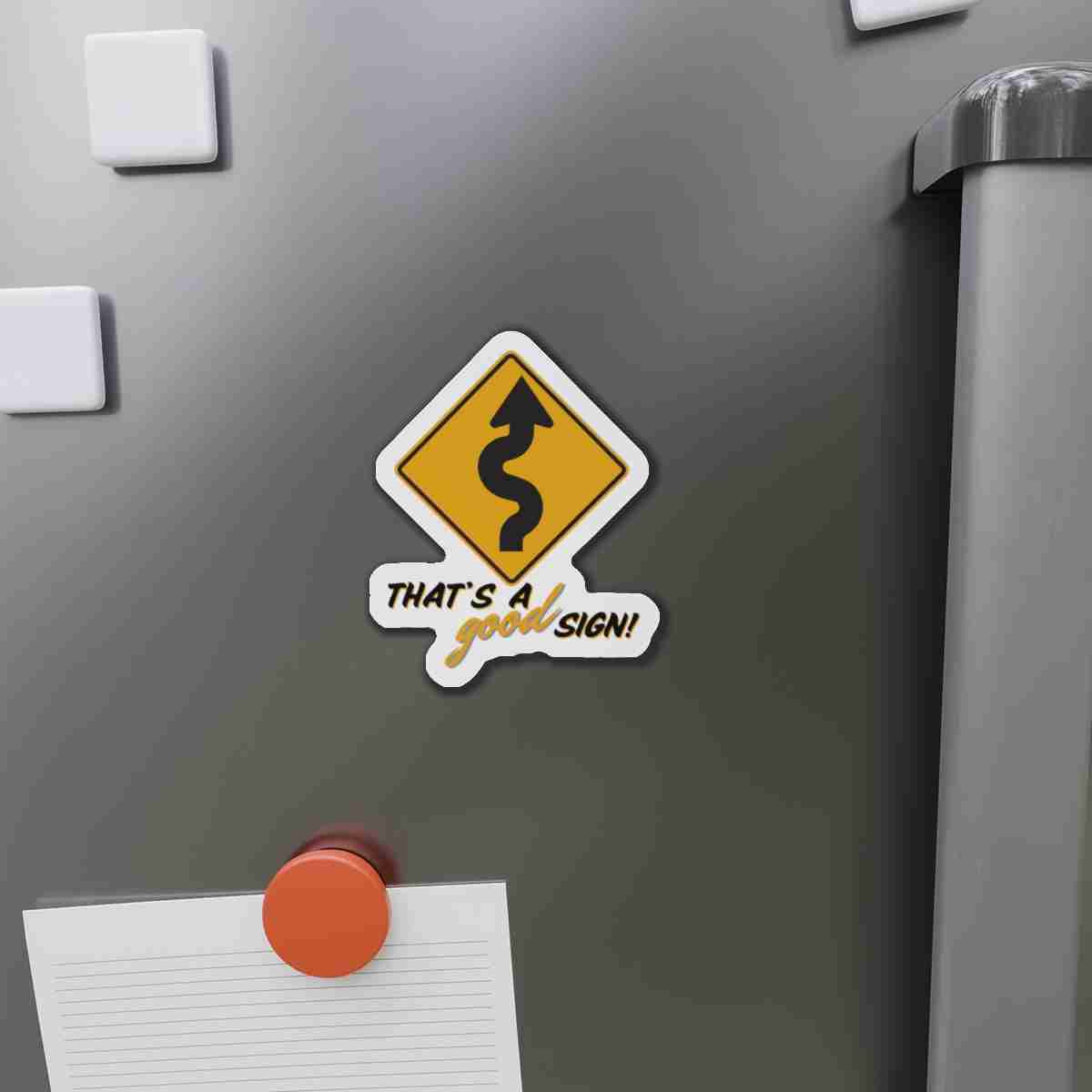 Sticker on a gray metal surface showing a yellow winding-road sign with the caption 'That's a good sign!'