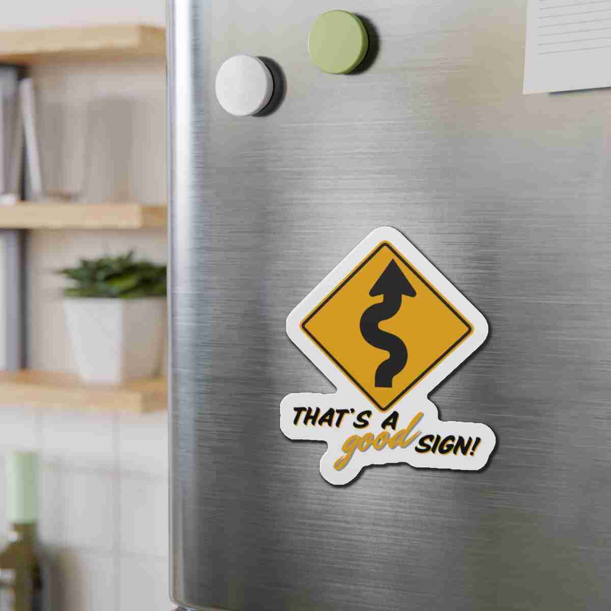 Refrigerator door with a yellow winding-road sign sticker reading 'That's a good sign!'