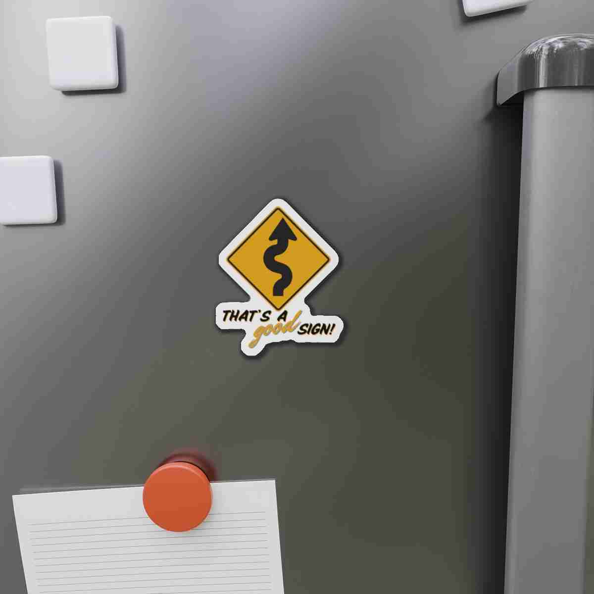 Sticker on a gray fridge: yellow diamond road-sign graphic with a winding arrow and the caption 'That's a good sign!'